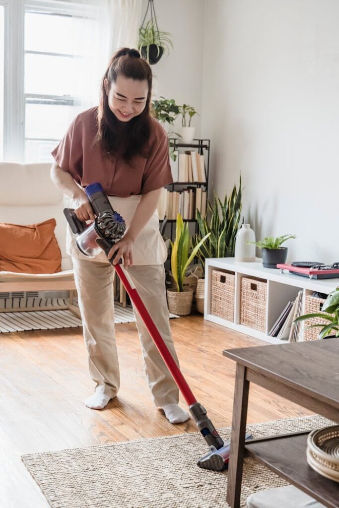 Smiling woman vacuuming a cozy living room with indoor plants.